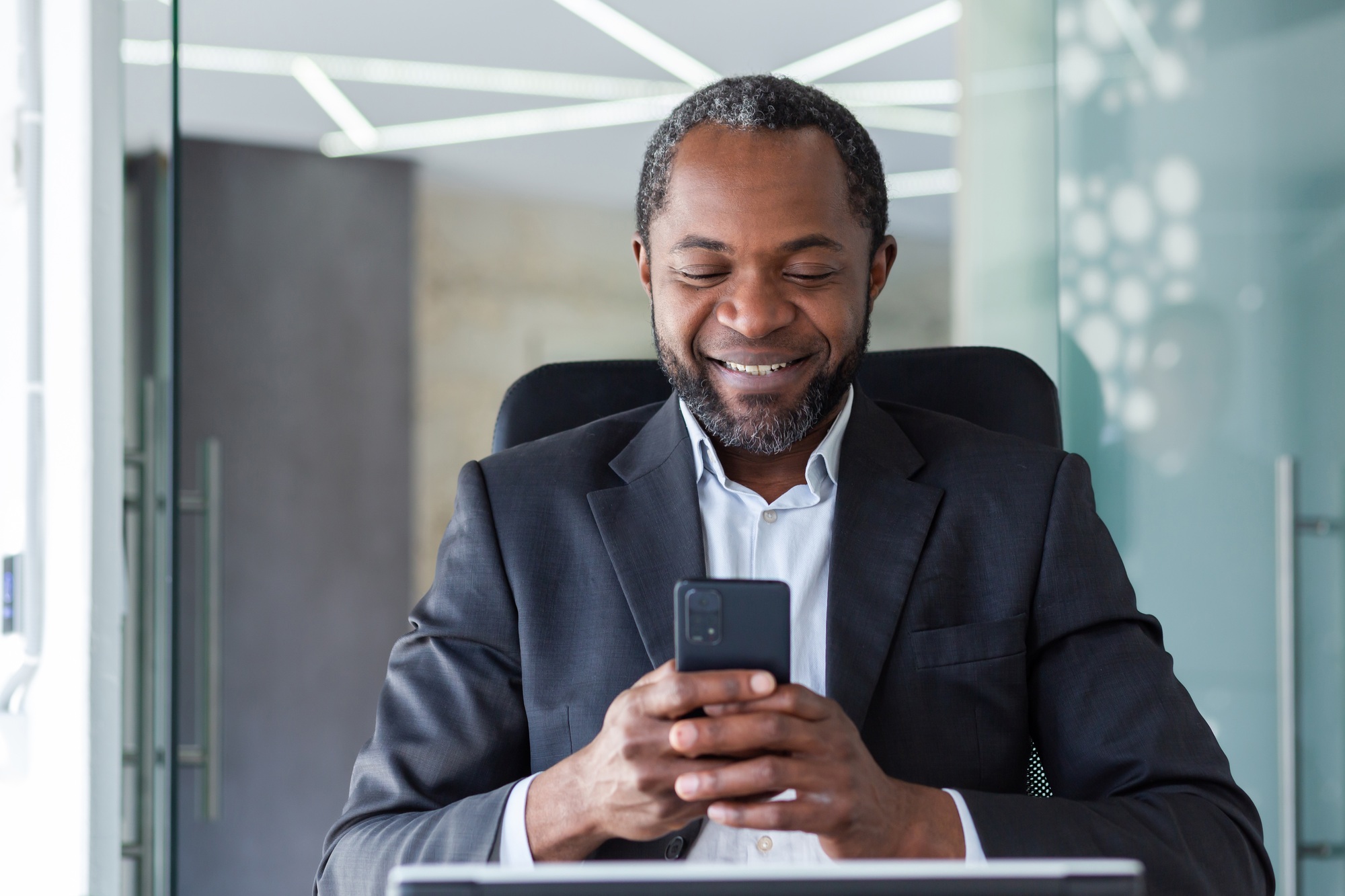 Close-up of an African-American man in the office uses an application on the phone, a businessman